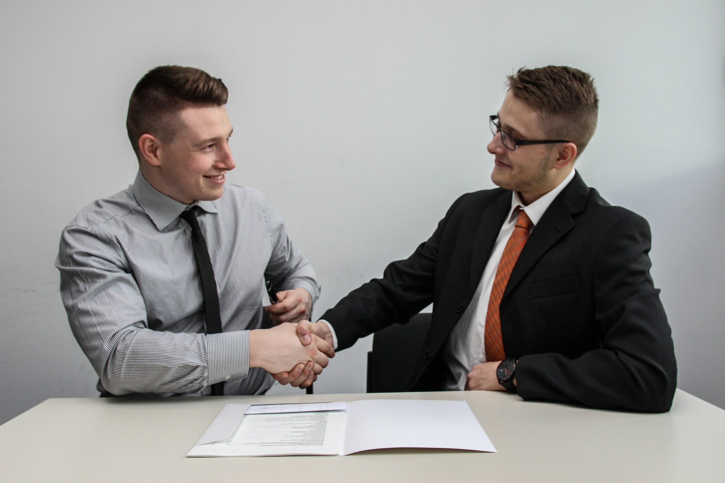 Foto de dois homens vestidos socialmente se cumprimentando em um aperto de mãos, ilustrando o artigo "como funciona o crédito consignado"