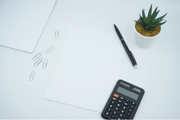 Foto de materiais sobre a mesa, incluindo calculadora, para calcular os ganhos e descobrir se vale a pena pedir empréstimo para investir.